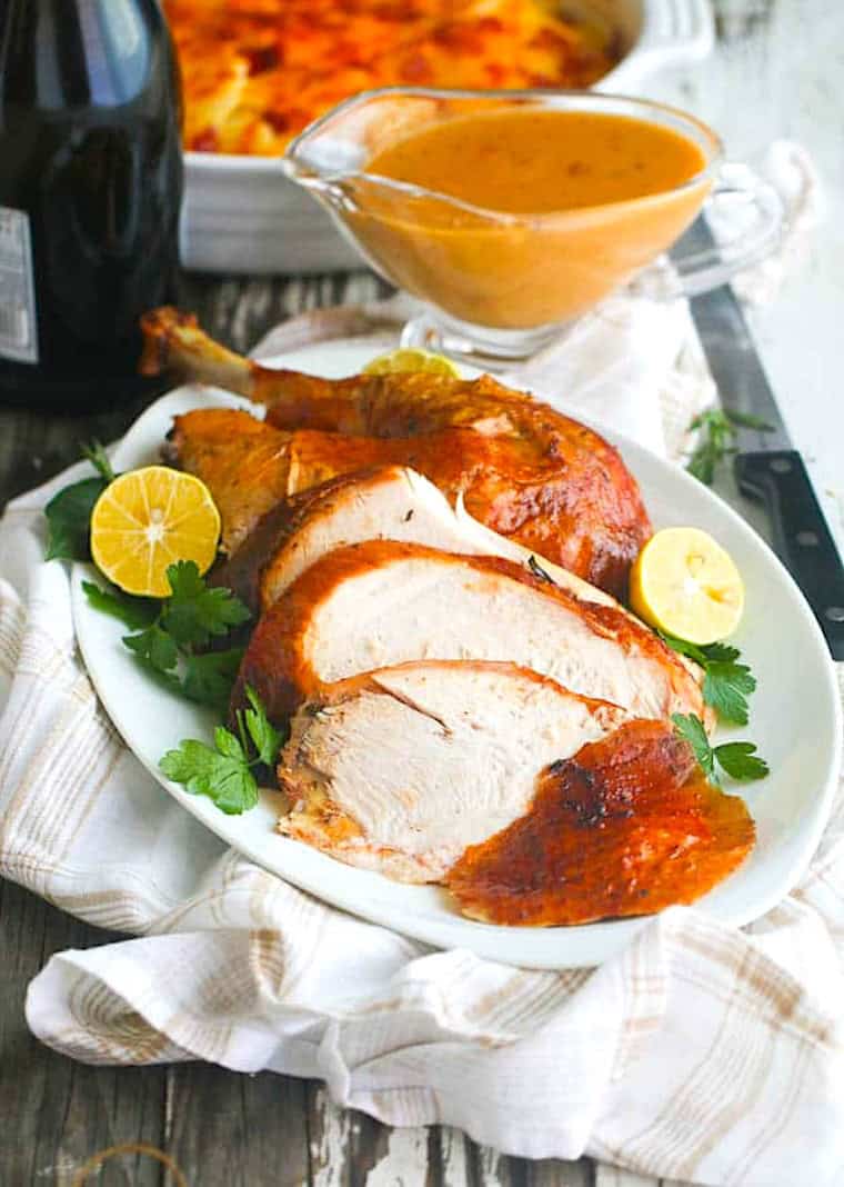 Beautifully roasted turkey on a white platter with gravy.