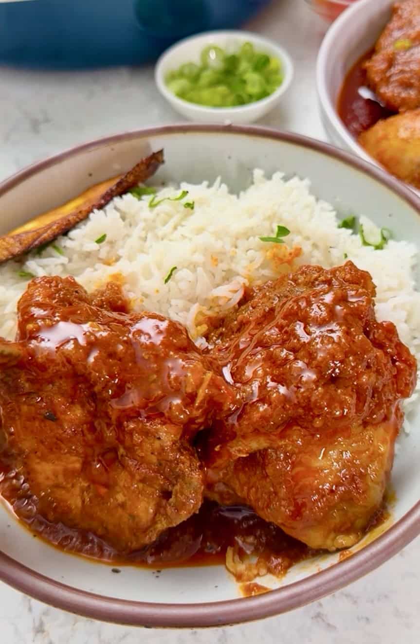 An African chicken dinner with a delicious tomato-based sauce, fried plantains, and coconut rice.