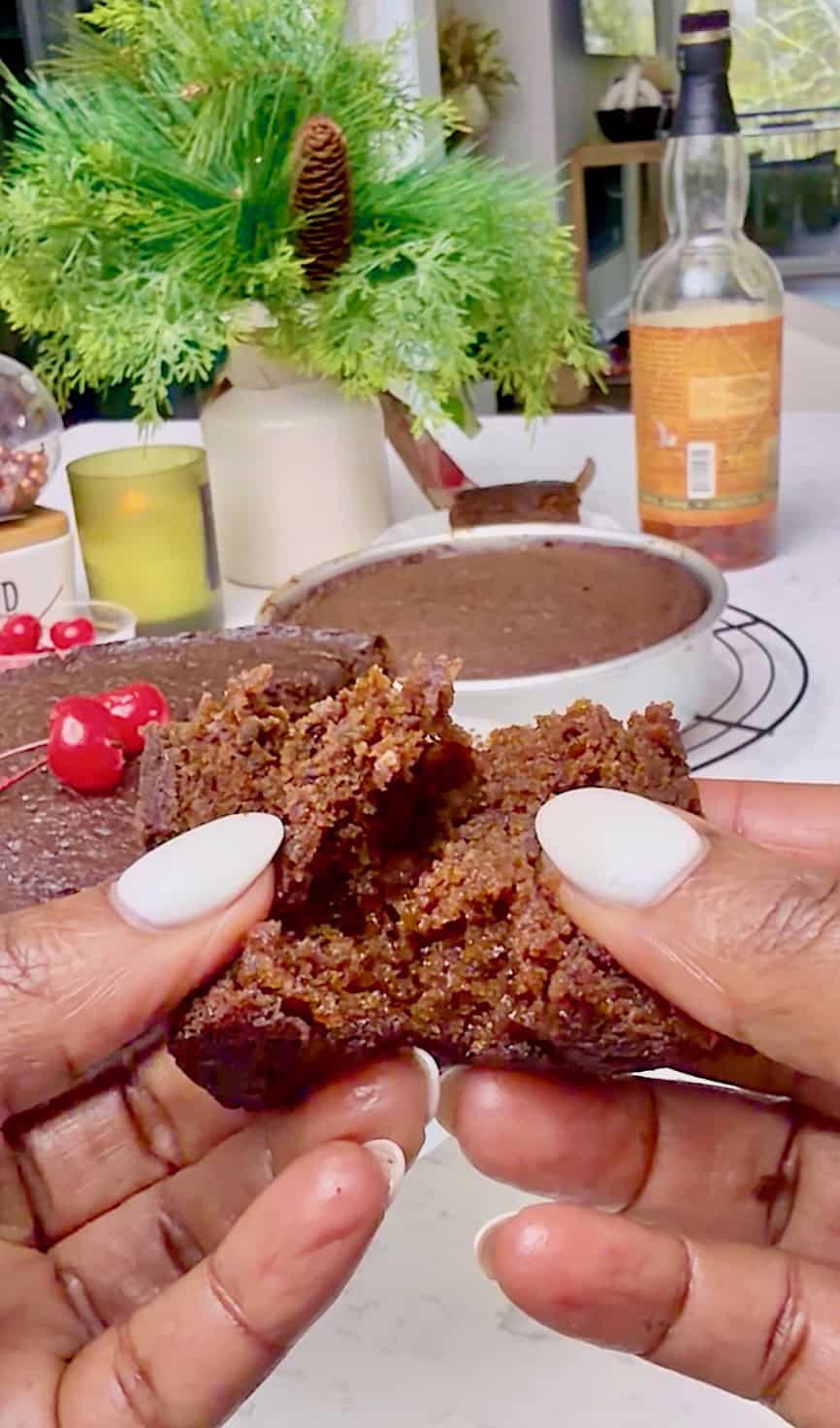 Breaking open a slice of a Christmas fruit cake to show off the moist dense interior.