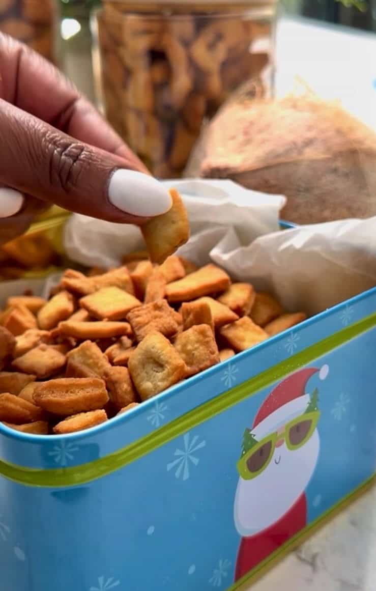 Taking a crispy, addictive chin chin from a Christmas tine.