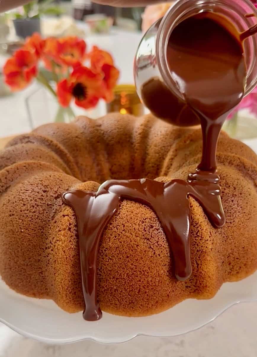 Drizzling chocolate glaze over the finished cake.