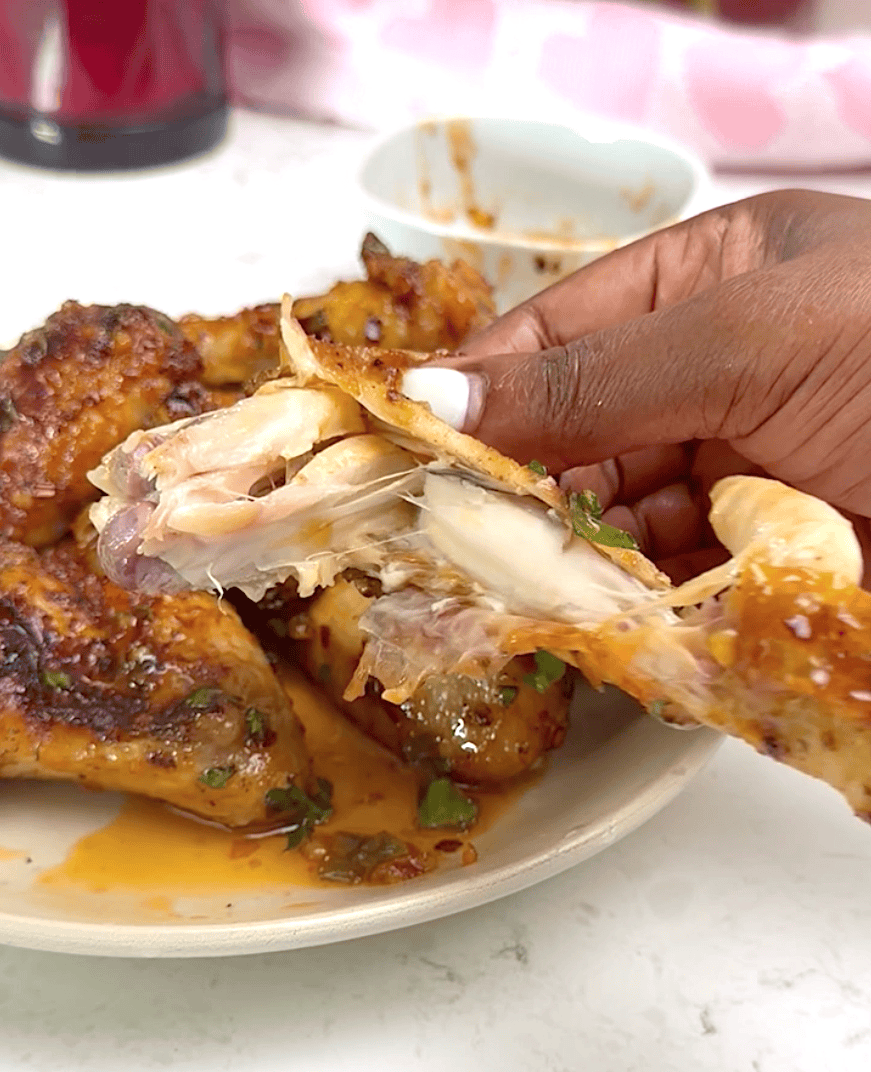 Tearing into a spicy, sweet, sticky chicken wing that's fall-off-the-bone tender.