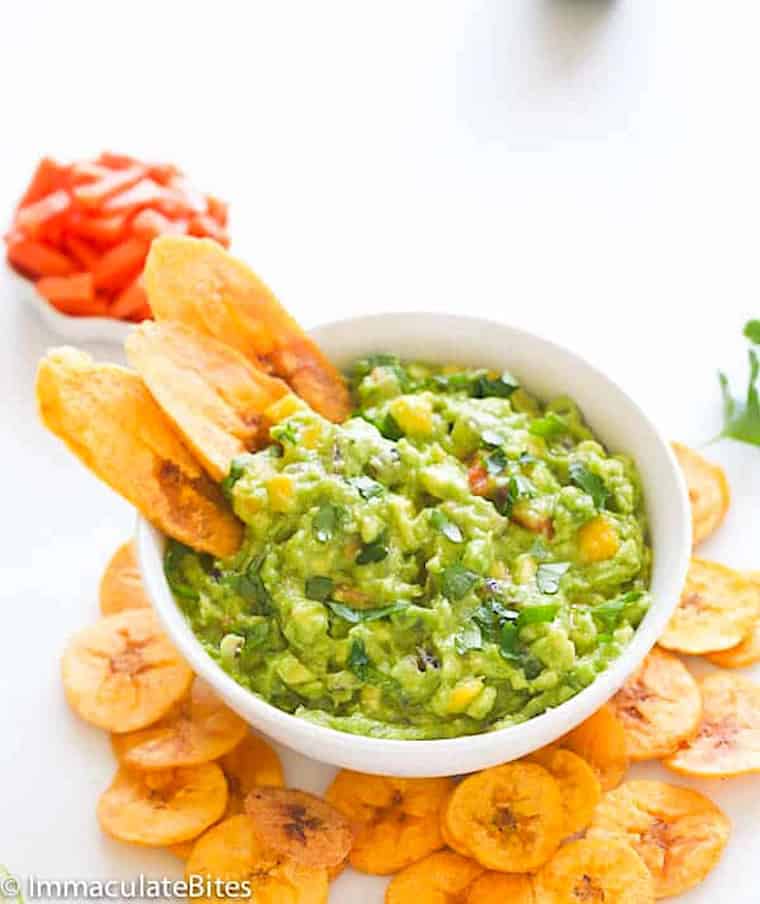 Enjoying baked plantain chips with guacamole and tropical fruit for a guilt-free appetizer.
