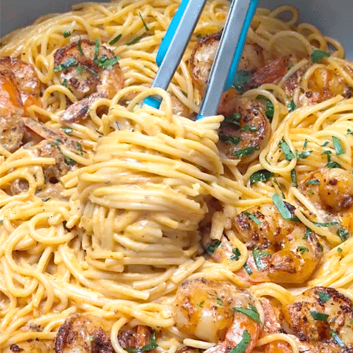 Twirling creamy shrimp pasta around tongs to serve up a decadent meal.