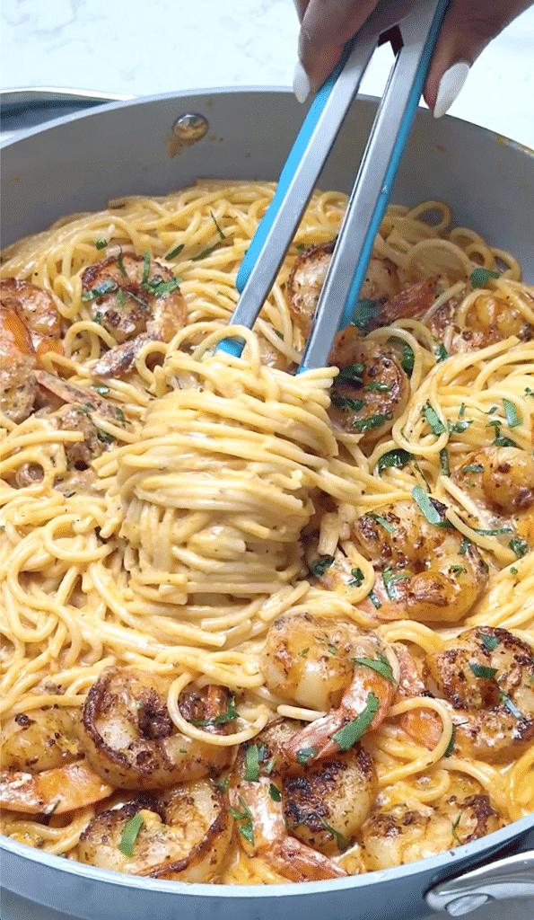 Twirling creamy shrimp pasta around tongs to serve up a decadent meal.