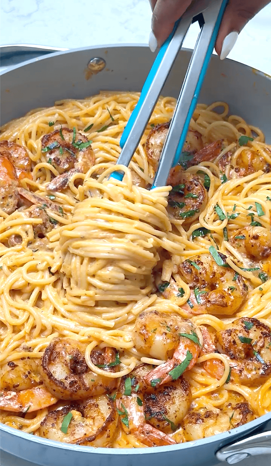 Twirling creamy shrimp pasta around tongs to serve up a decadent meal.