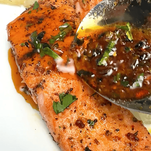 Drizzling more sauce over freshly baked salmon.