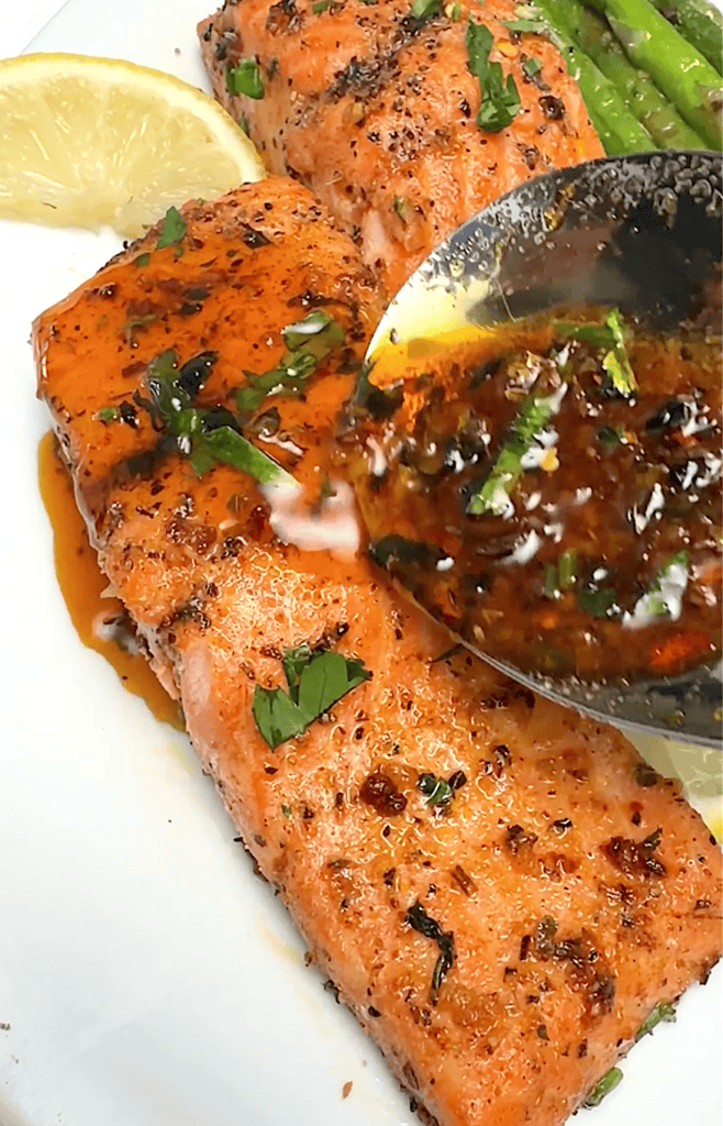 Drizzling more sauce over freshly baked salmon.
