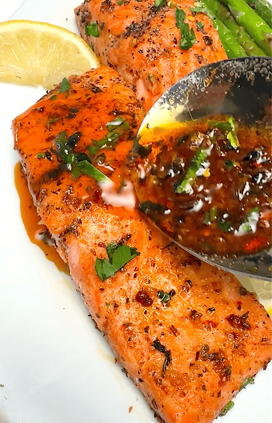 Drizzling more sauce over freshly baked salmon.