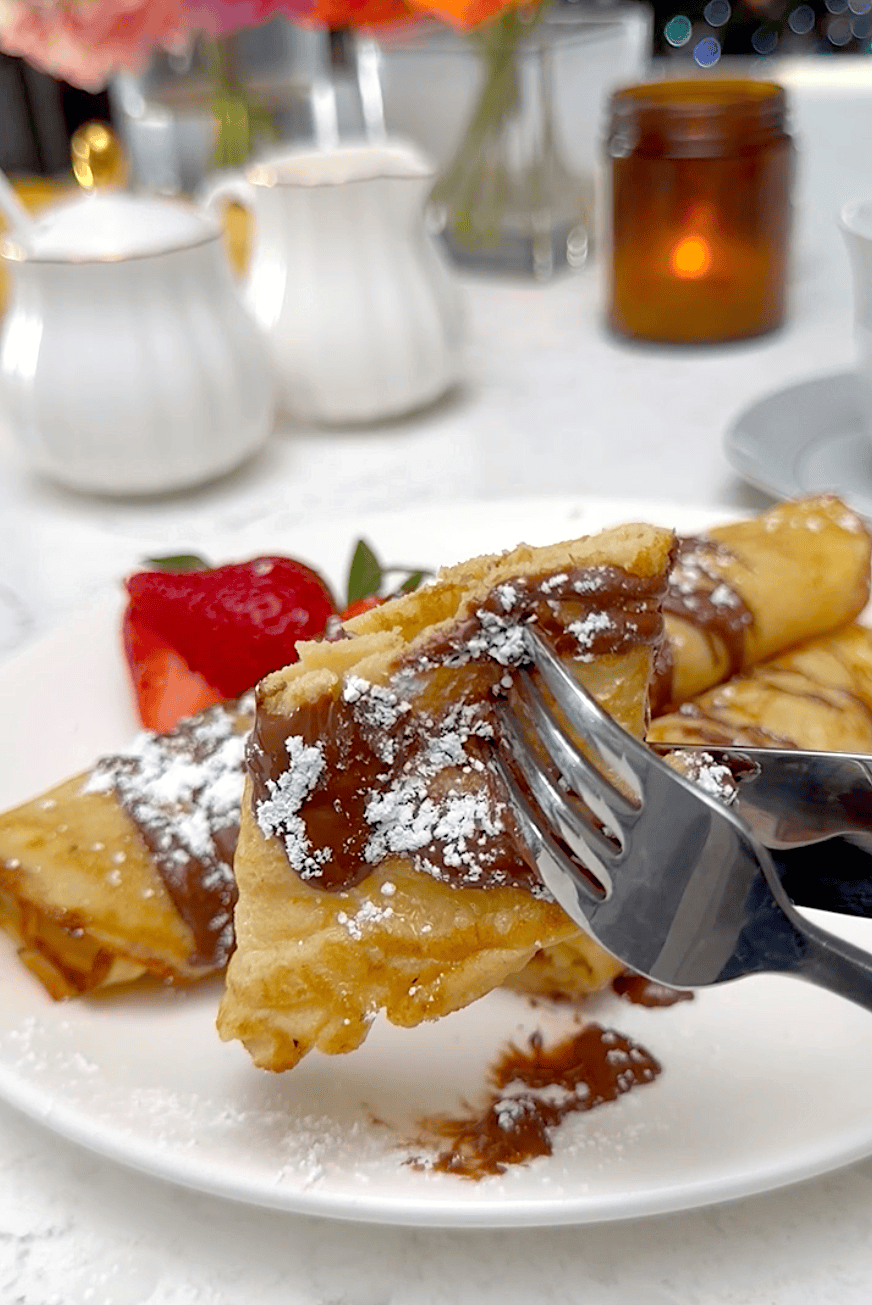 Forking into freshly rolled plantain crepes topped with chocolate sauce and powdered sugar.