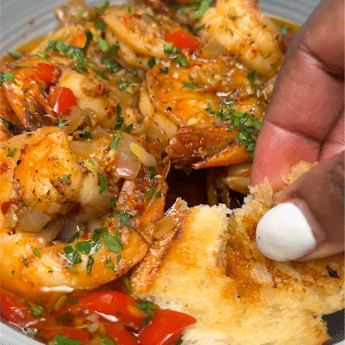 Dipping fresh garlic bread into the decadent shrimp scampi sauce.