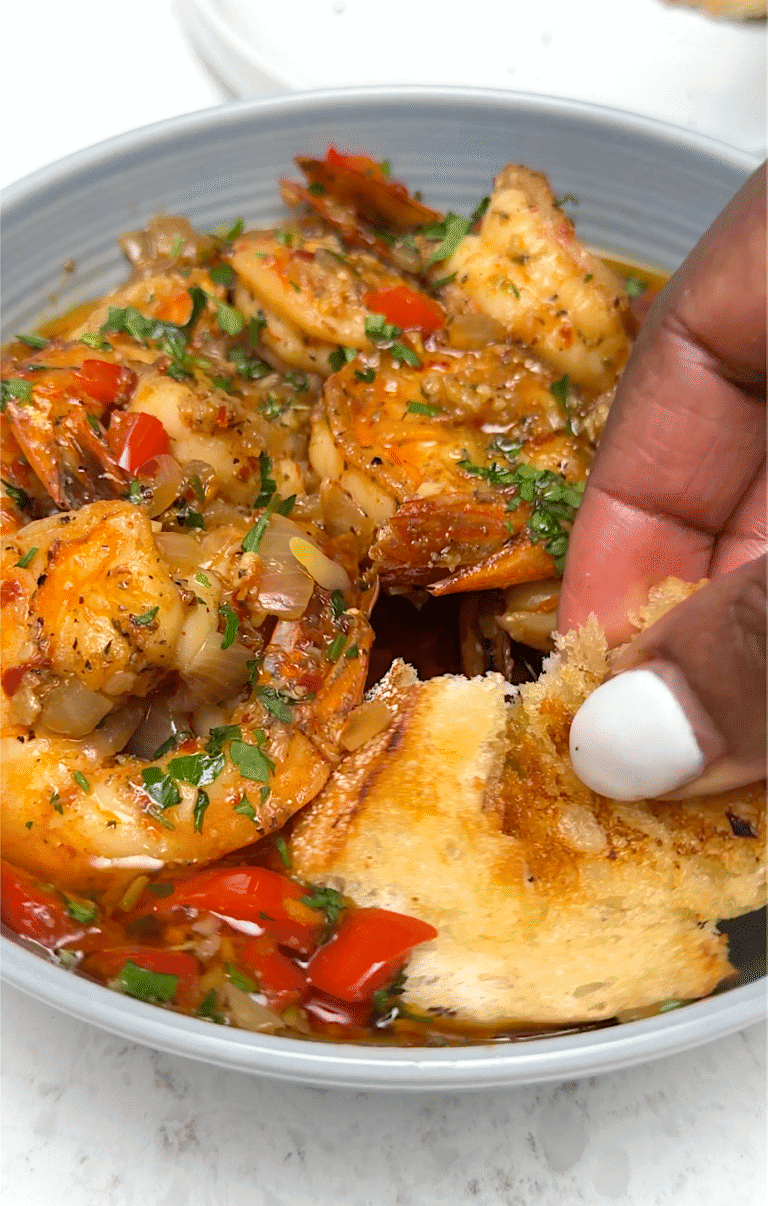 Dipping fresh garlic bread into the decadent shrimp scampi sauce.