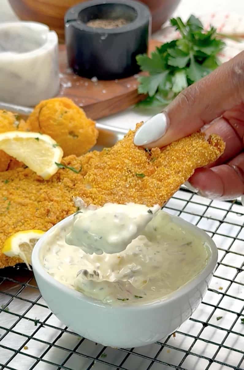 Dipping freshly fried fish into spicy tartar sauce.