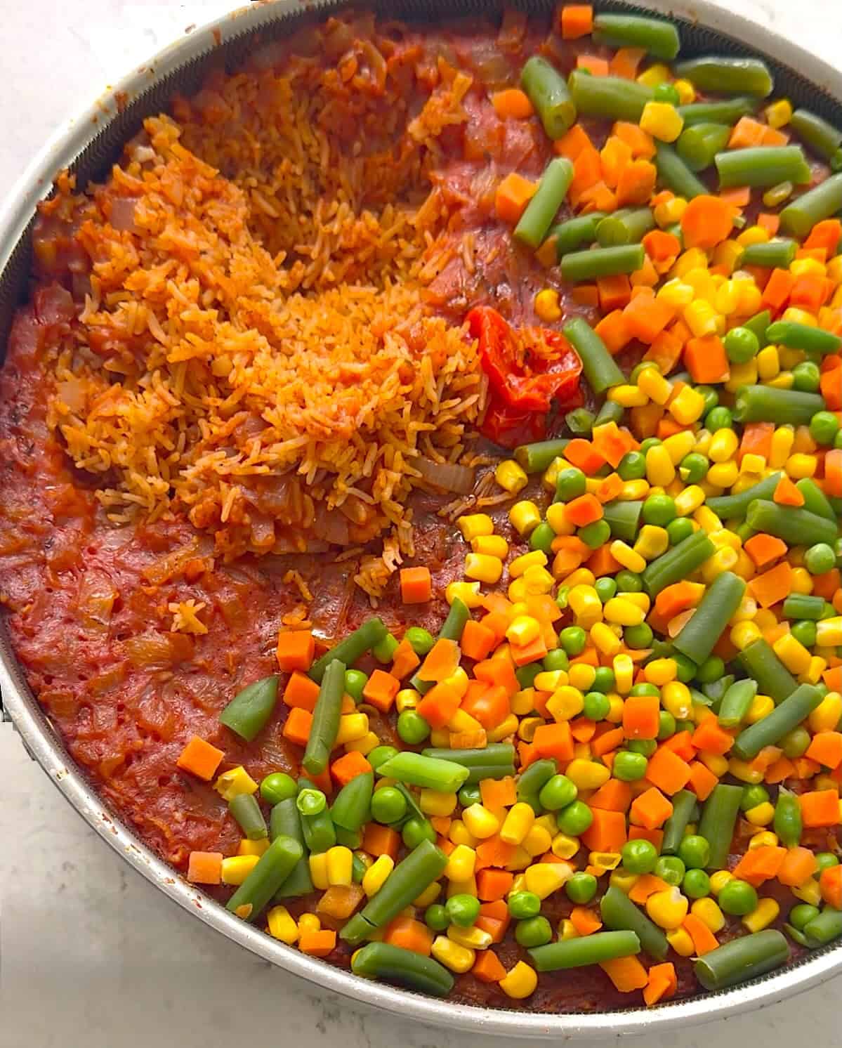 Fluffing jollof rice with steamed vegetables, then enjoying it with beef skewers.