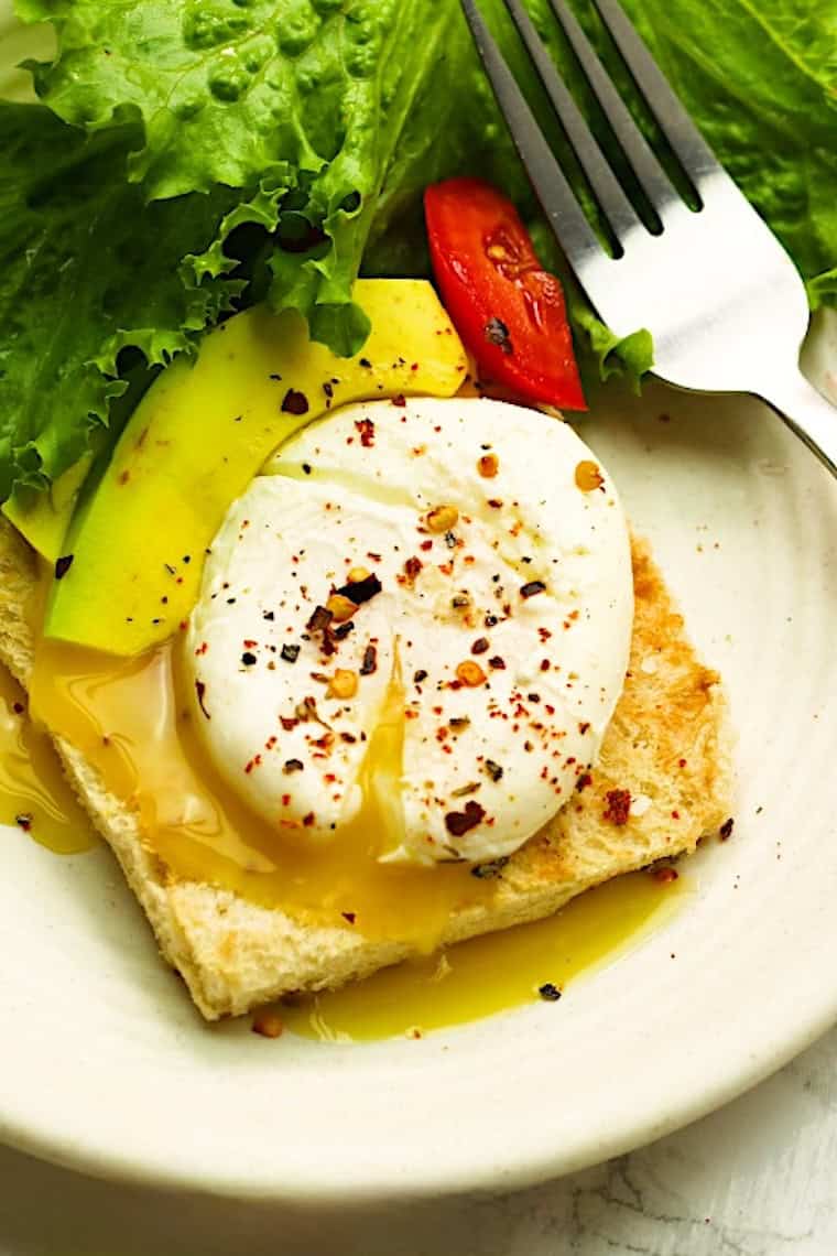 A perfectly runny yolk of a poached egg tops avocado toast and a refreshing salad.