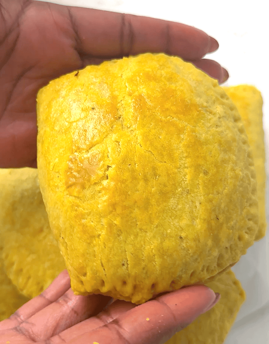 Imma excitedly holding a freshly baked beef pie made Jamaican style.