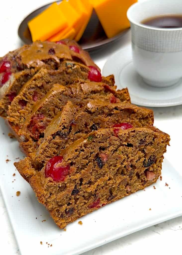 Festive Jamaican Easter spice bun sliced and ready to enjoy with cheddar cheese and coffee.