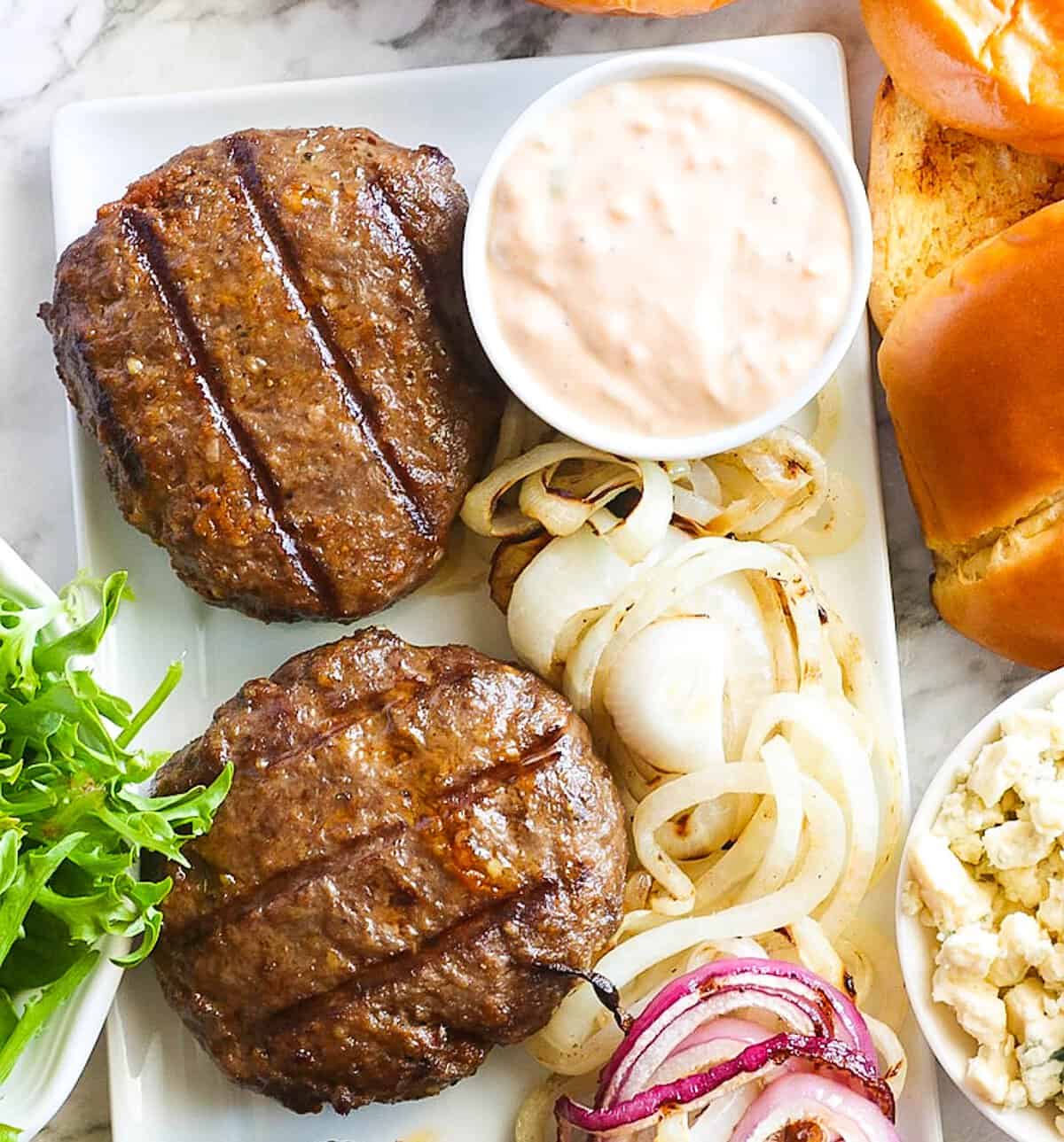 Topping a smoked burger with a homemade awesome sauce.