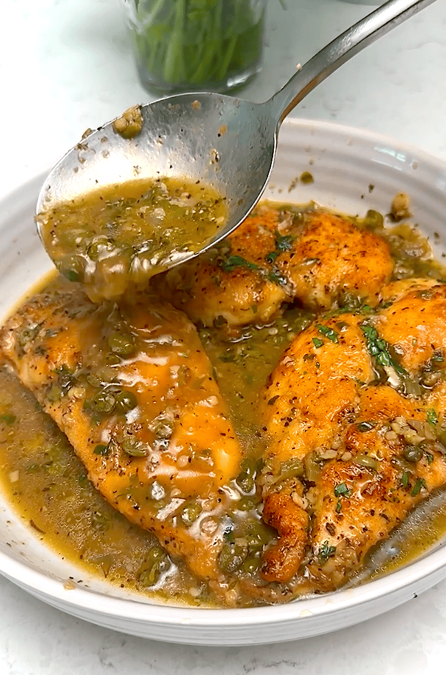 Drizzling sauce over chicken piccata, ready to serve over pasta for an elegant dinner.
