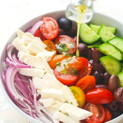 Drizzling a fresh salad with Greek olive oil dressing.