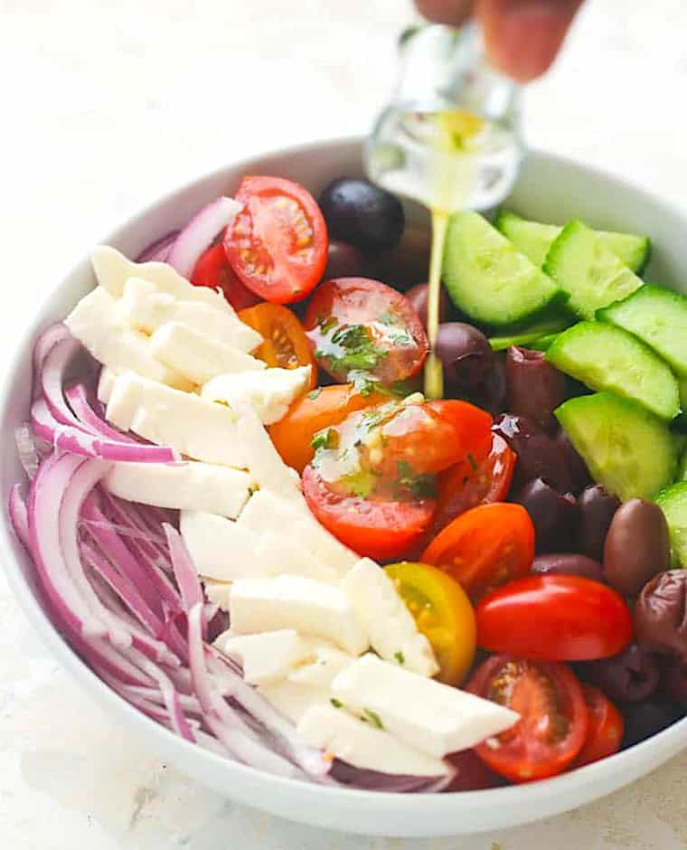Drizzling a fresh salad with Greek olive oil dressing.