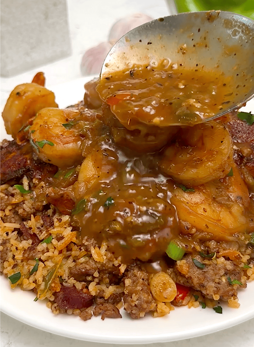 Drizzling thick etouffee sauce over shrimp and rice.