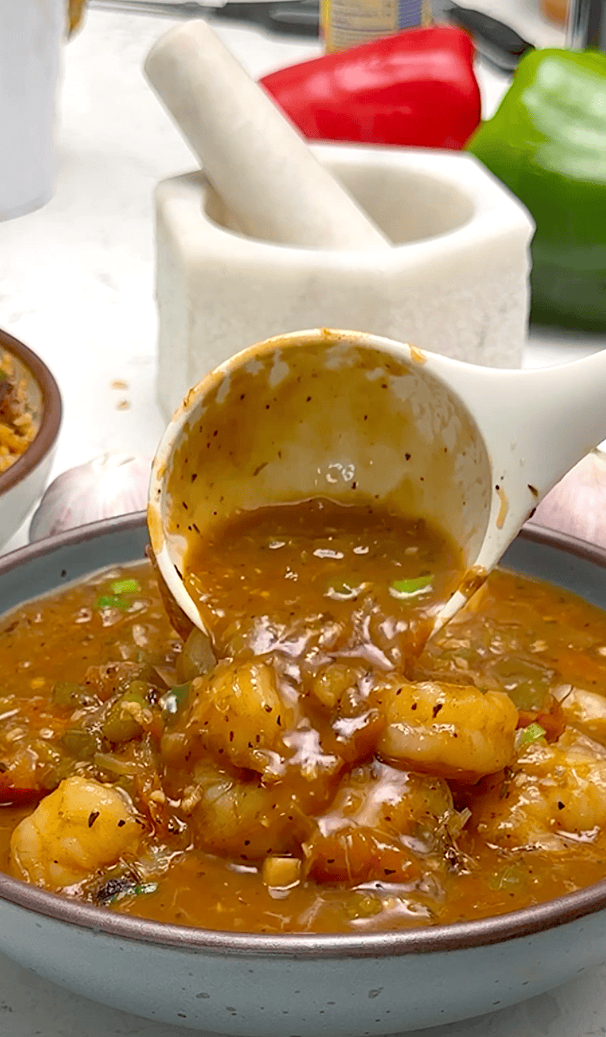 Adding the thickened gravy over the perfectly cooked shrimp etouffee.