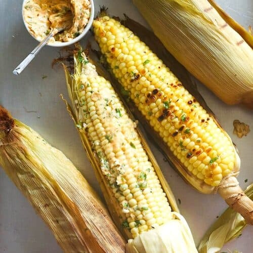 Slathering smoky, juicy corn on the cob with spicy herbed butter.