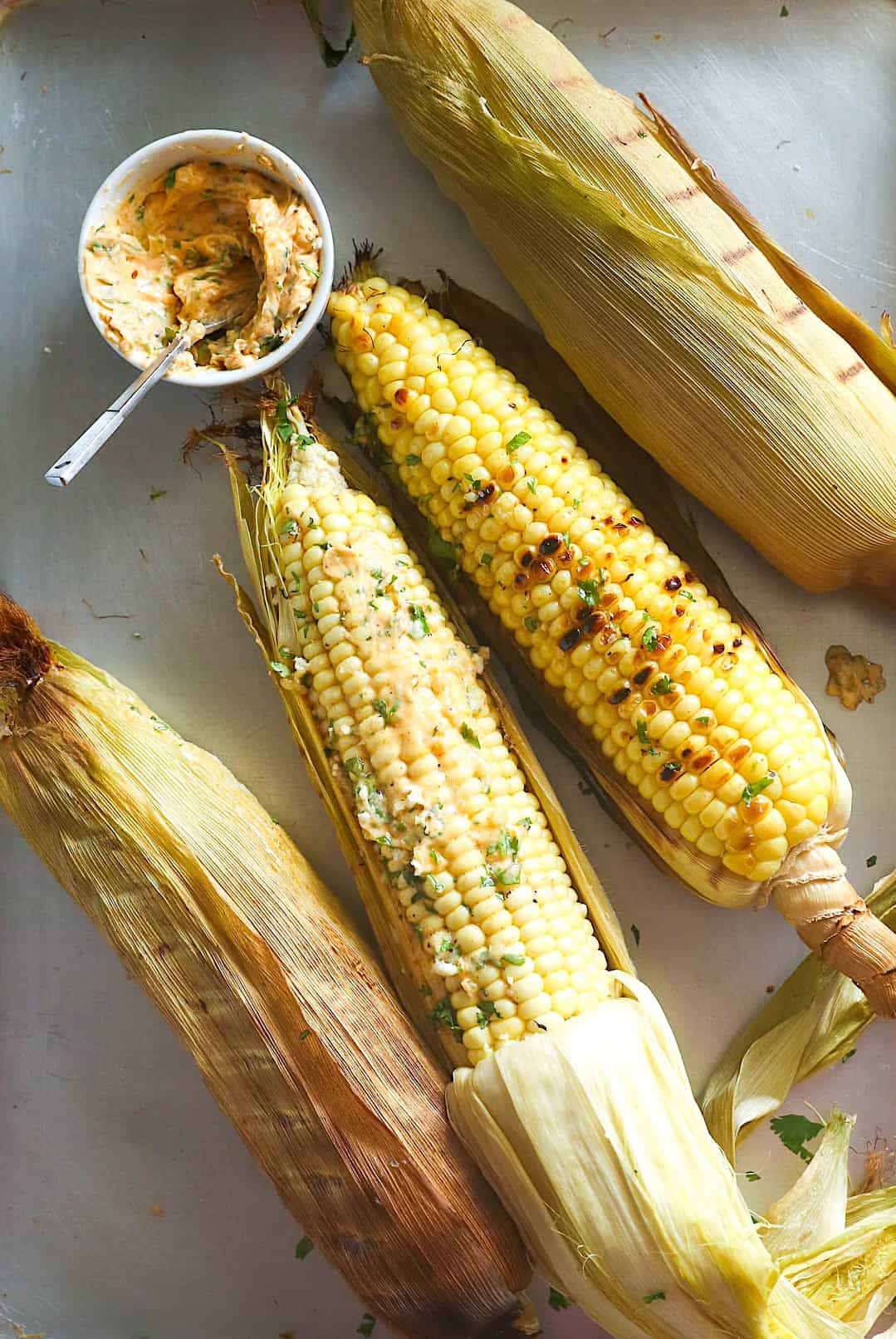 Slathering smoky, juicy corn on the cob with spicy herbed butter.