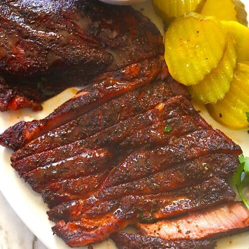 Slicing into a pork steak fresh from the smoker for an economical cookout element.