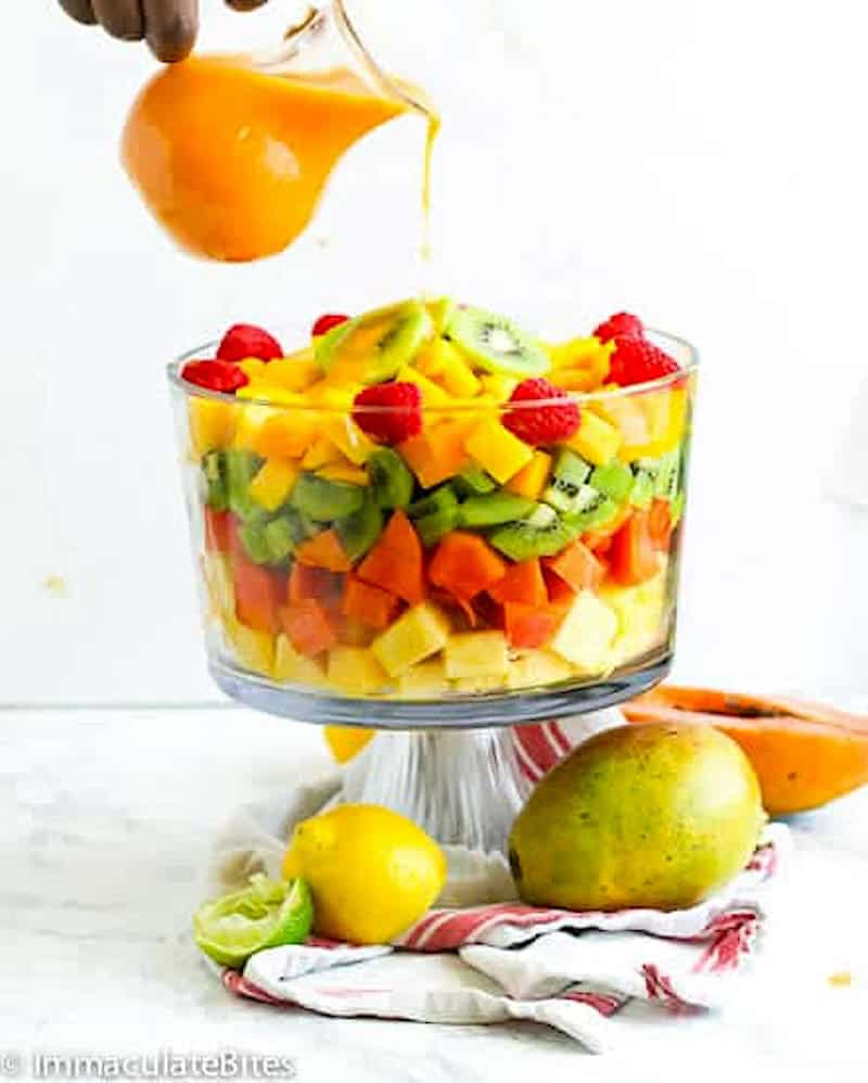 Drizzling a fruity dressing over a tropical fruit salad for a refreshing breakfast or dessert.