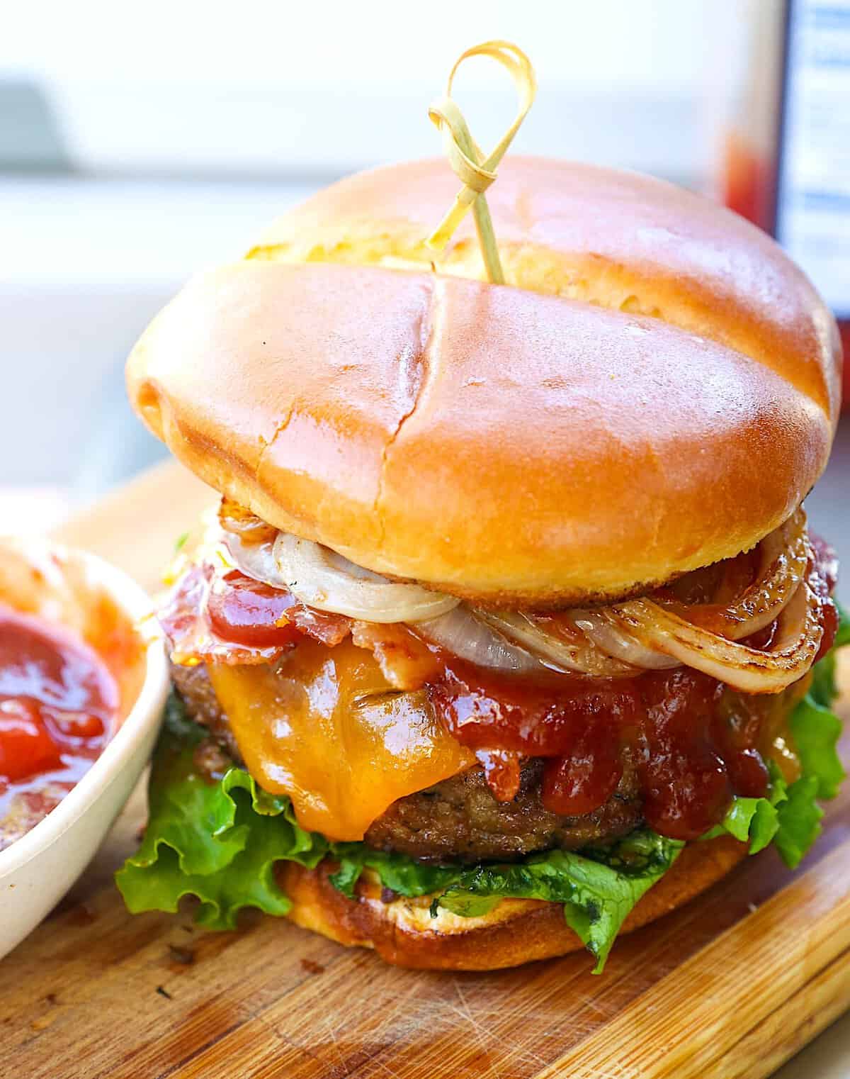 Loading up a flavorful burger with grilled onions and homemade BBQ sauce.