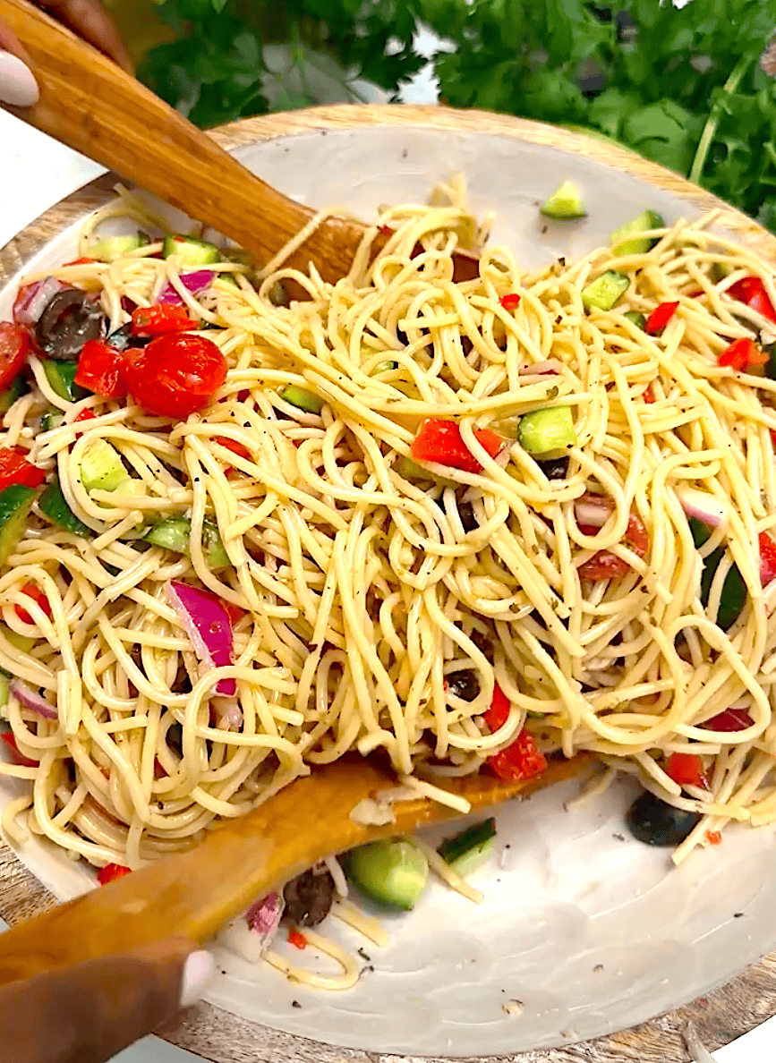Tossing a salad with hearty spaghetti and fresh vegetables in an Italian salad dressing.