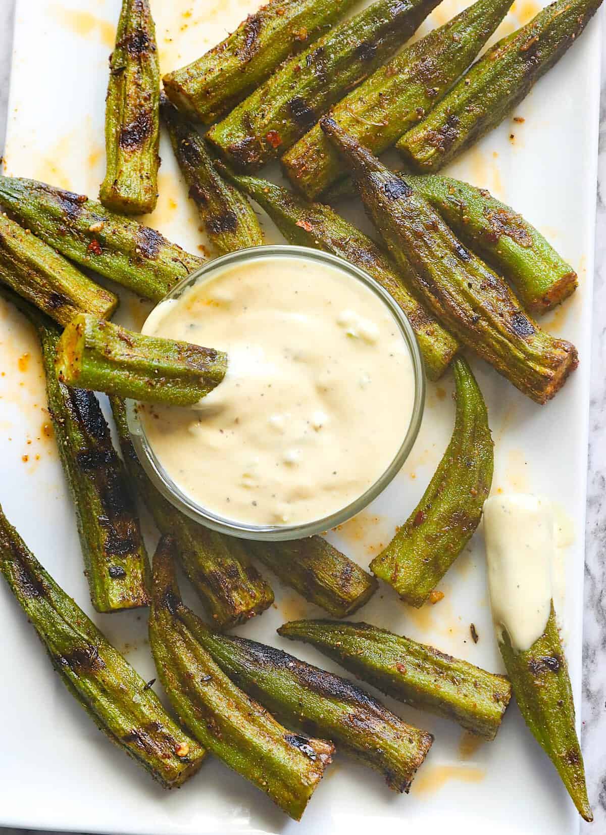 Enjoying a remoulade dipping sauce with grilled okra.