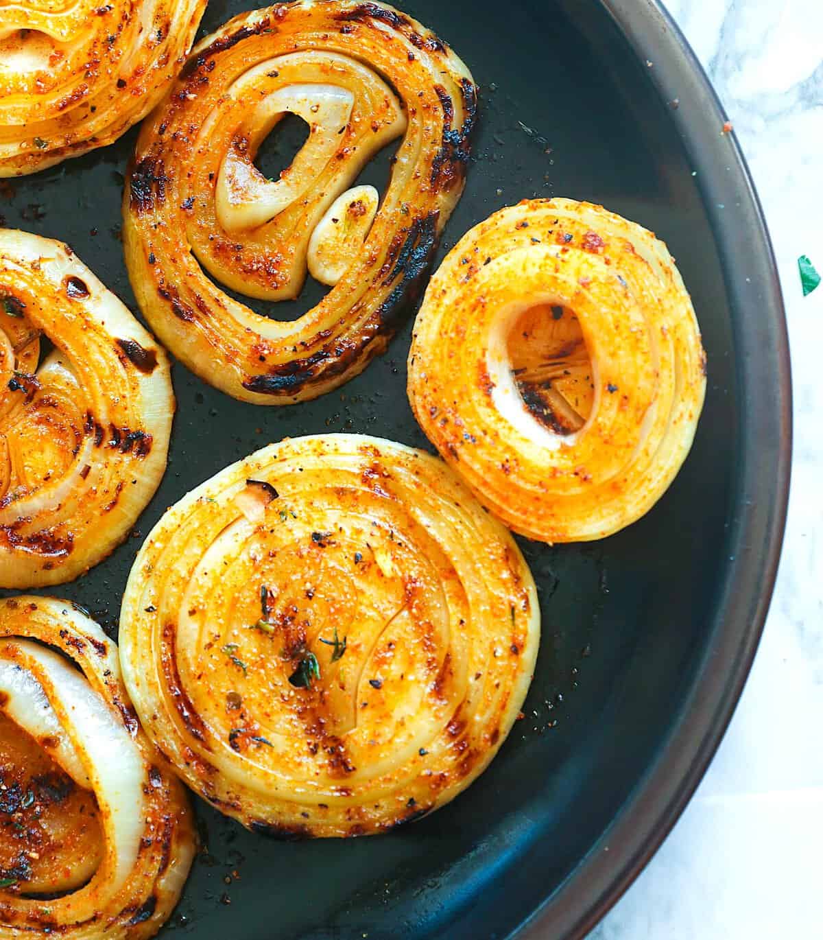A plate full of grilled onions ready to spice up a roast beef sandwich.