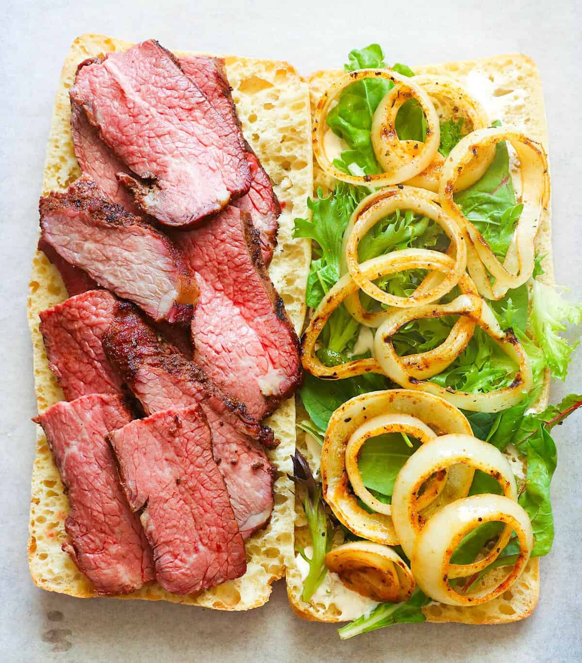 Stacking grilled onions on a roast beef sandwich for extra flavor.