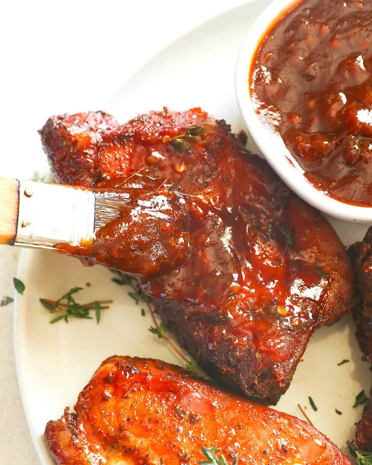 Brushing grilled pork with homemade BBQ sauce.