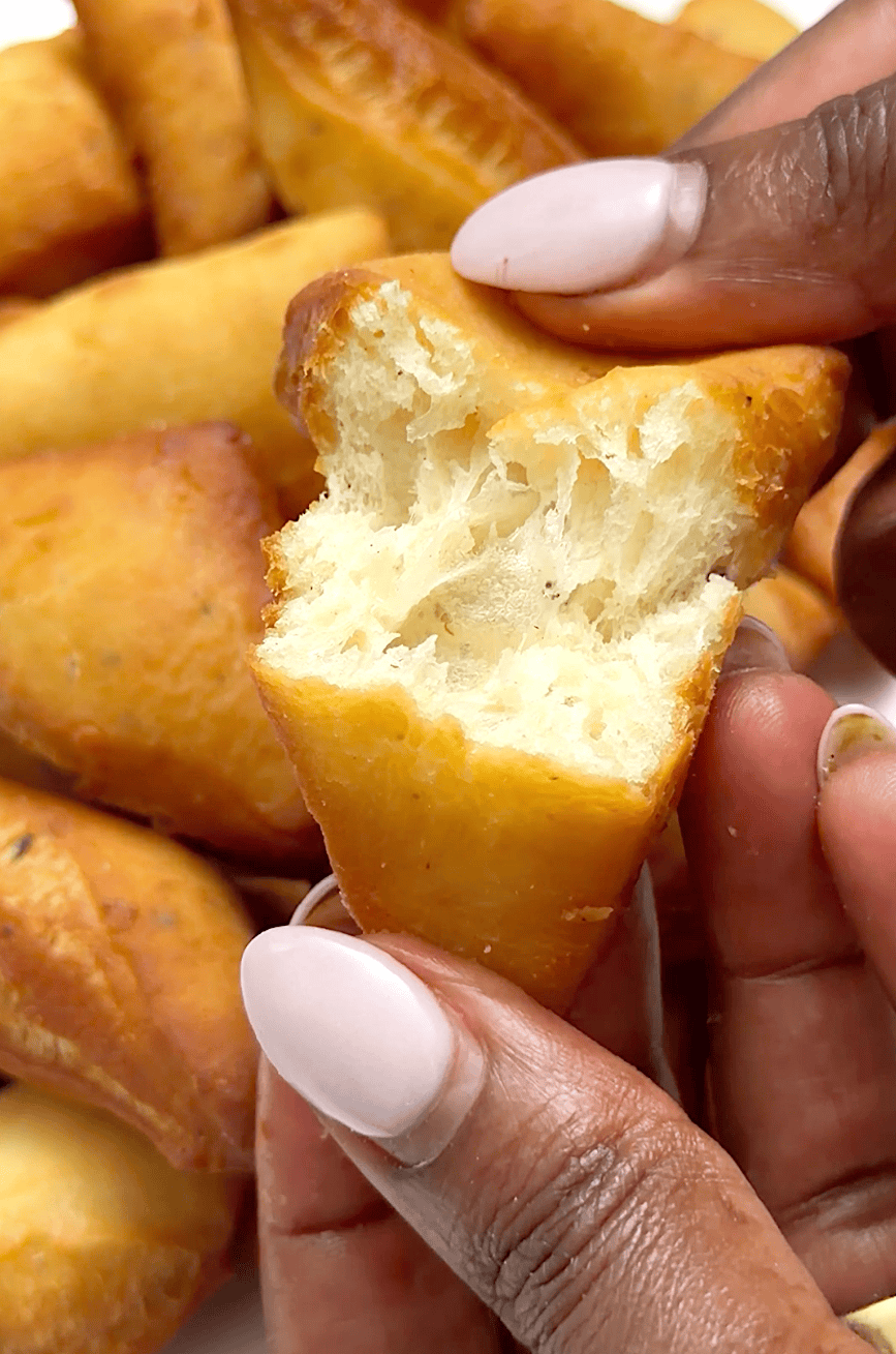 Breaking into a freshly fried mandazi (East African doughnuts).