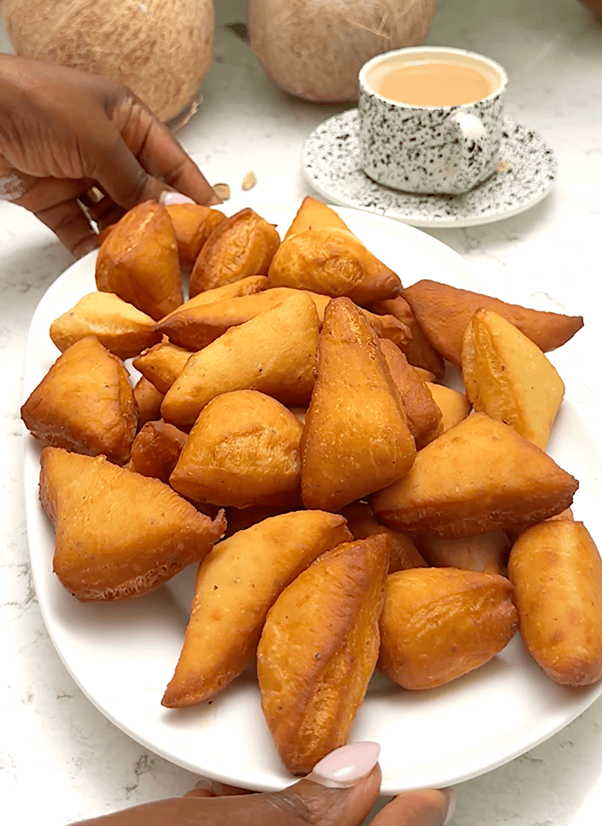 A plateful of freshly fried mandazi waiting to be dusted with powdered sugar.