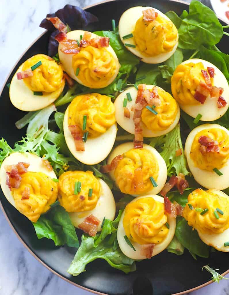 Serving up a platter of smoked deviled eggs topped with bacon for a family picnic.
