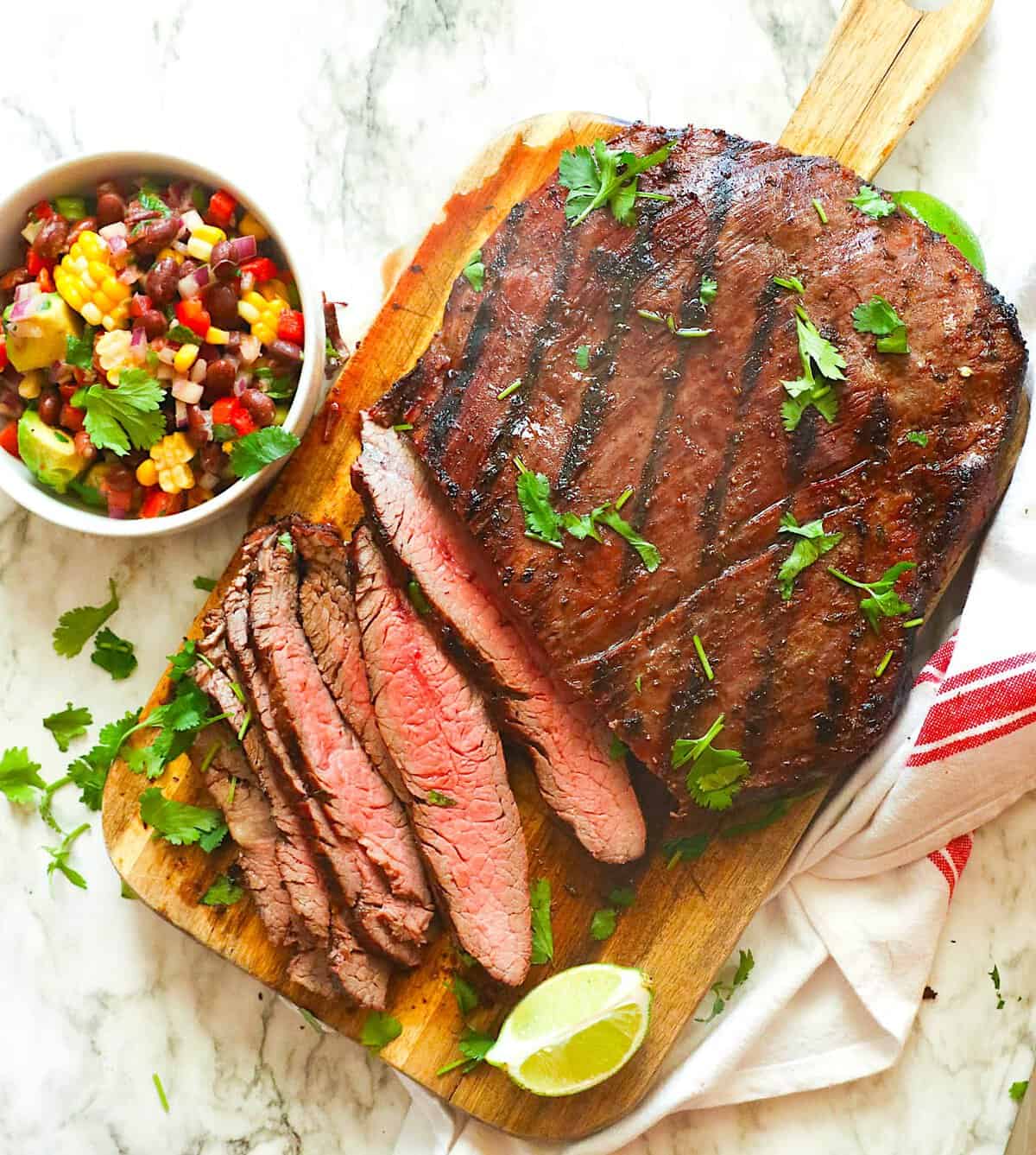 Slicing into a perfectly smoked and reverse seared flank steak. Black bean and corn salsa sits on the side ready and waiting.