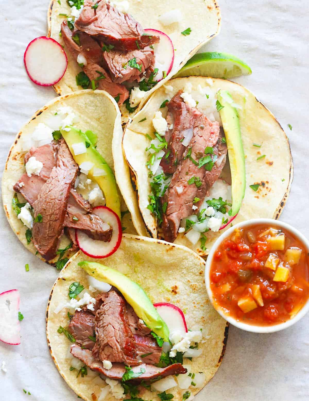 Making amazing tacos with sliced flank steak and all the fixings.