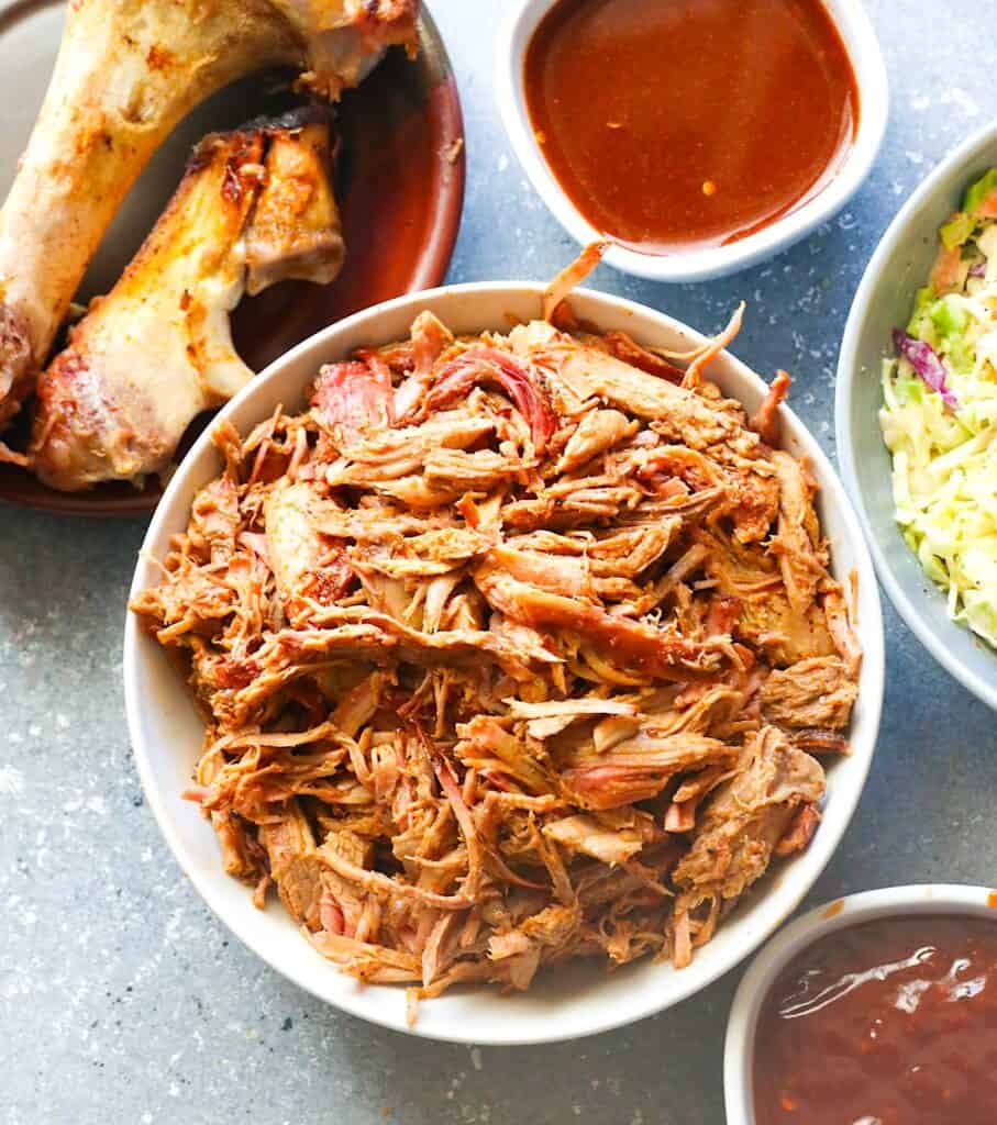 A serving bowl full of smoked pulled pork ready for classic comfort food sandwiches.