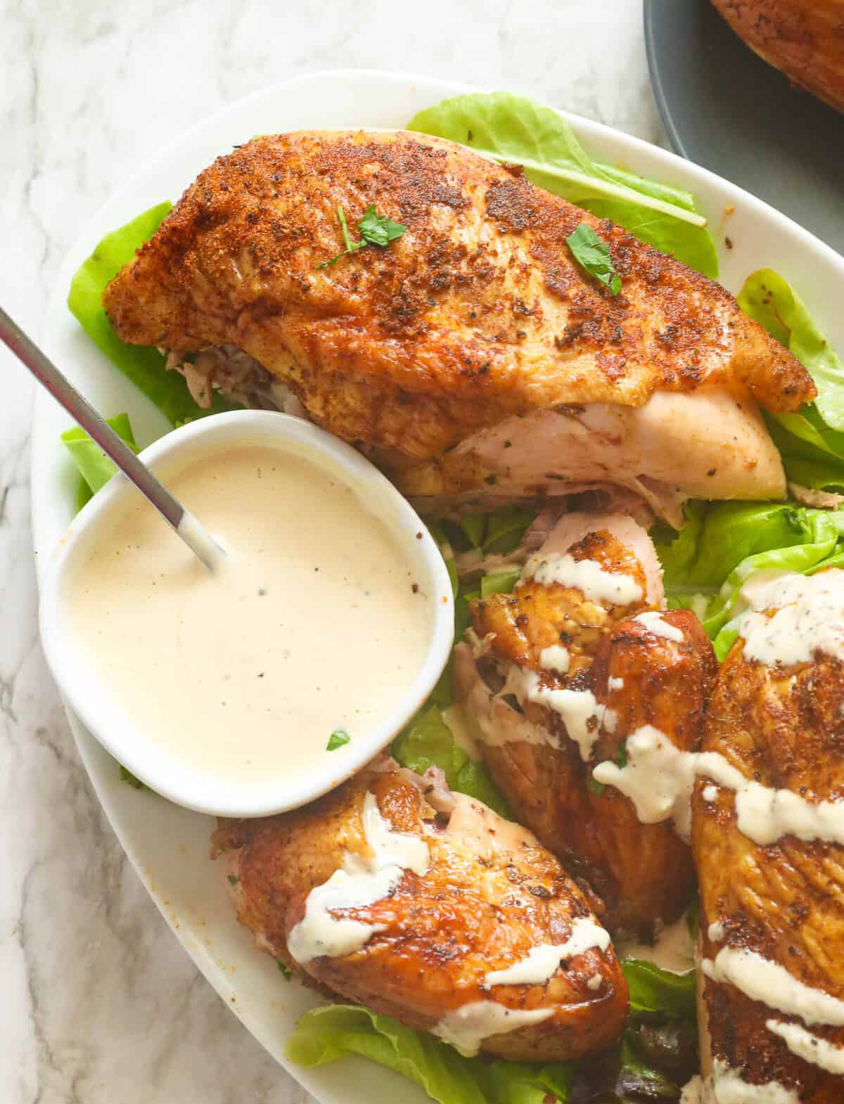 Drizzling homemade white BBQ sauce over freshly smoked chicken for an amazing comfort food meal.