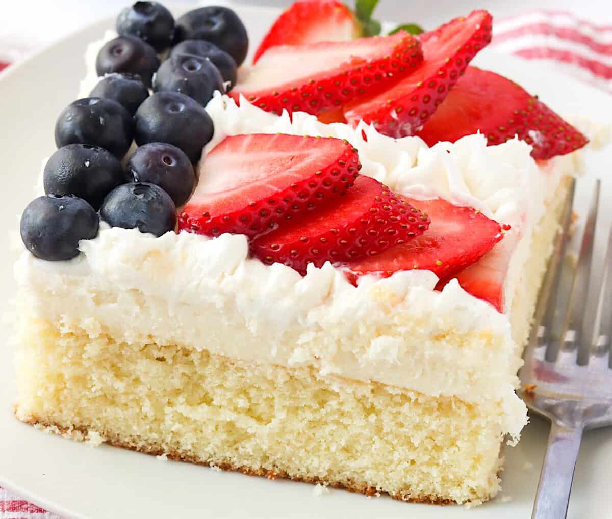 Serving up a satisfying slice of cake decorated like the American flag with strawberries and blueberries.