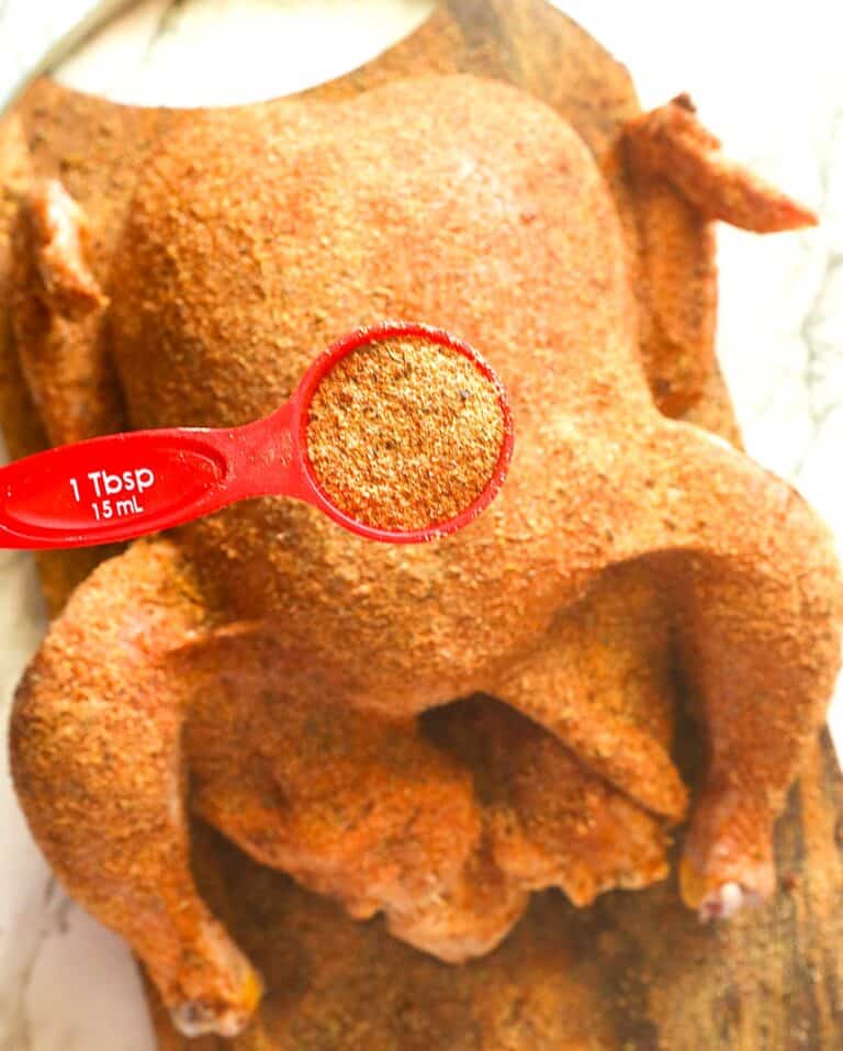 Covering a whole chicken with chicken dry rub for an easy flavor-packed meal.