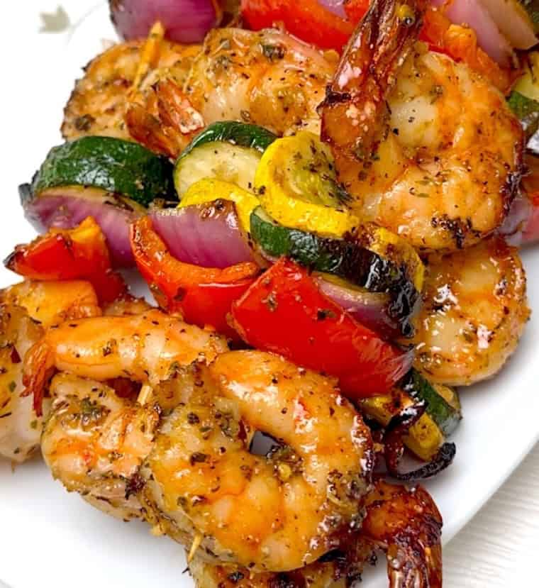 A closeup on tender, perfectly grilled shrimp on skewers.