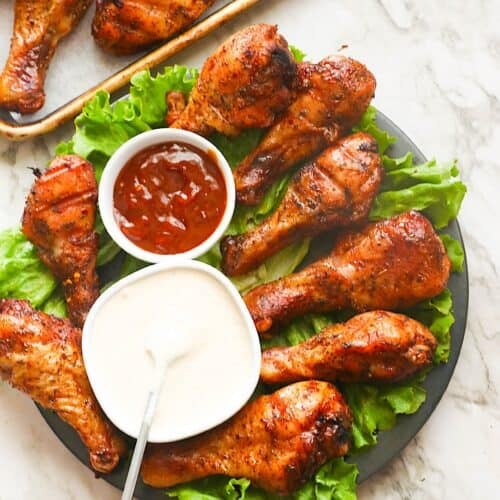 Serving up a platter loaded with pellet grill chicken legs and a side of white and honey BBQ sauce.