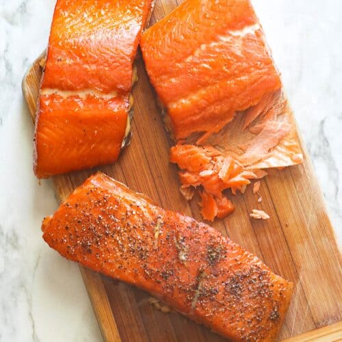 Flaky, moist salmon fresh from the smoker on a wooden cutting board.