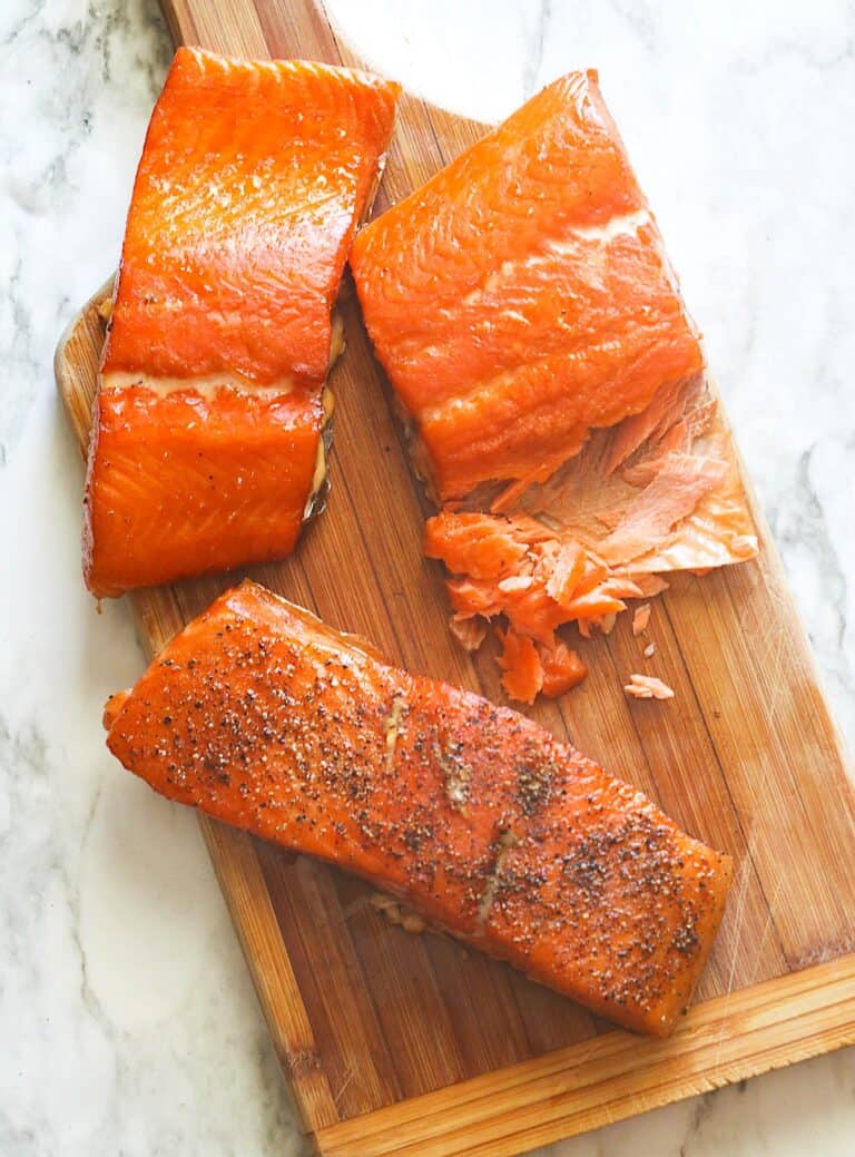 Flaky, moist salmon fresh from the smoker on a wooden cutting board.